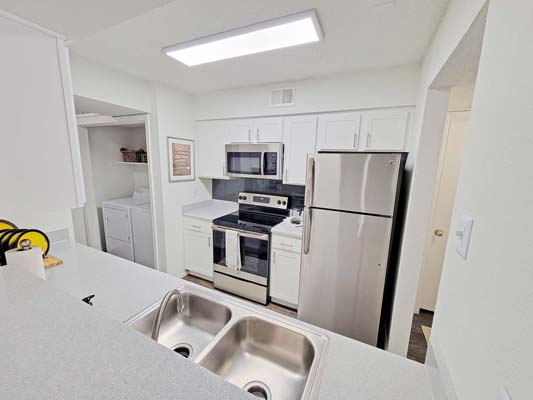 Kitchen with stainless steel appliances. Adjacent to laundry area with connections for a full size washer and dryer.