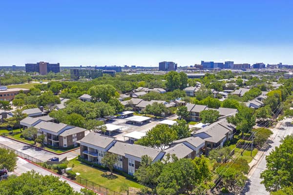 Drone shot of entire apartment community showing well established trees, lots of shaded areas, as well as covered parking for a majority of the community. Reserved covered parking is included.