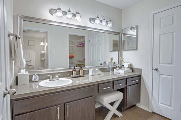 Bathroom with a large vanity, custom mirror frame, and nickel hardware, fixtures, and lighting.